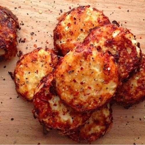 several pieces of pizza sitting on top of a wooden cutting board next to pepper flakes