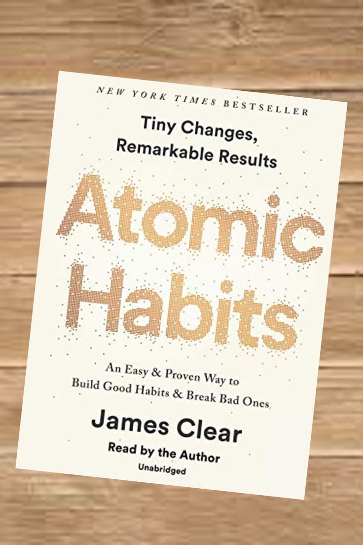 the book cover for atomic habitts by james clear on a wooden table with an orange and