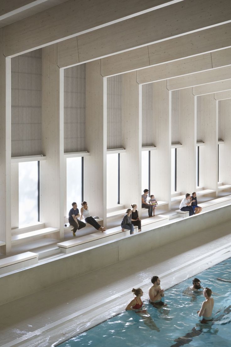 people are sitting and swimming in a large pool with windows on the side of it