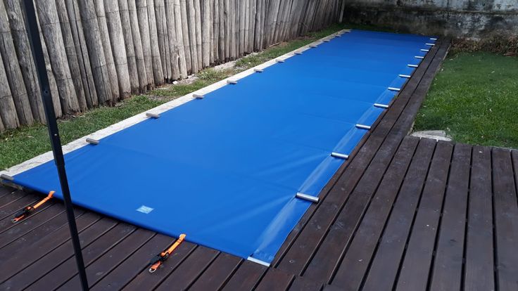 an inflatable pool is being installed on a wooden deck near a backyard fence