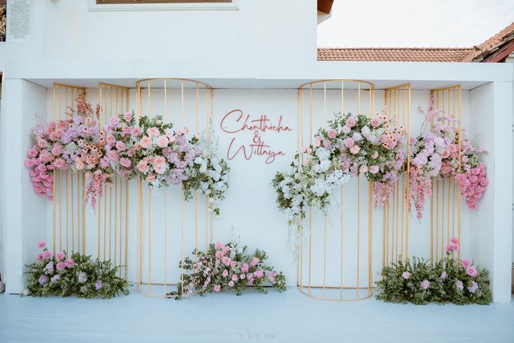 a white wall with pink flowers hanging from it's sides and the words charlotte & william written on it