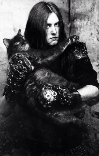 black and white photograph of a man with long hair holding a cat in his arms