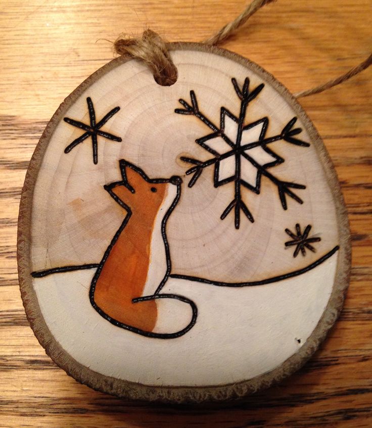 a wooden plaque with a fox and snowflakes on it's side in the shape of a circle