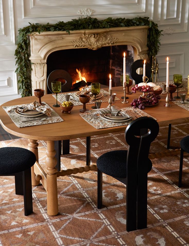 a dining room table set with place settings and candles on the fireplace mantels