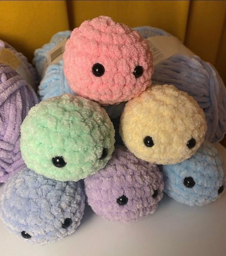 crocheted balls of yarn with eyes are arranged in a pile on a table