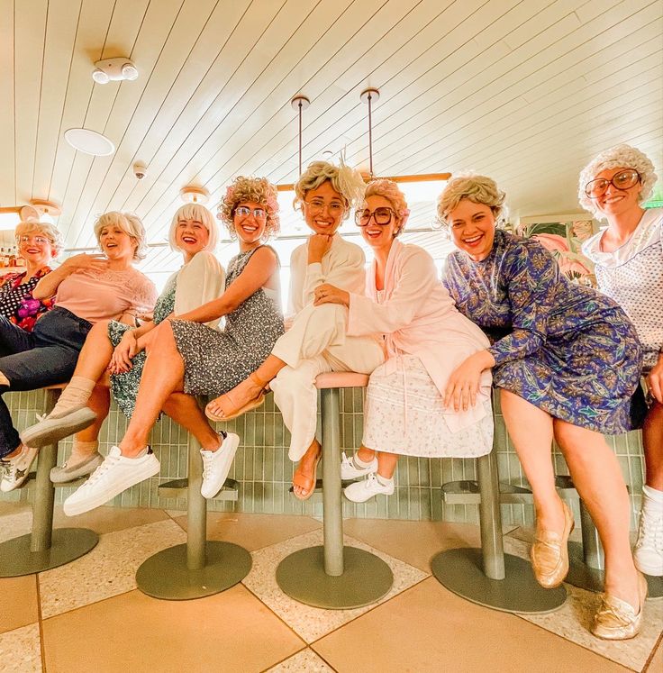 a group of older women sitting next to each other on top of a metal bench