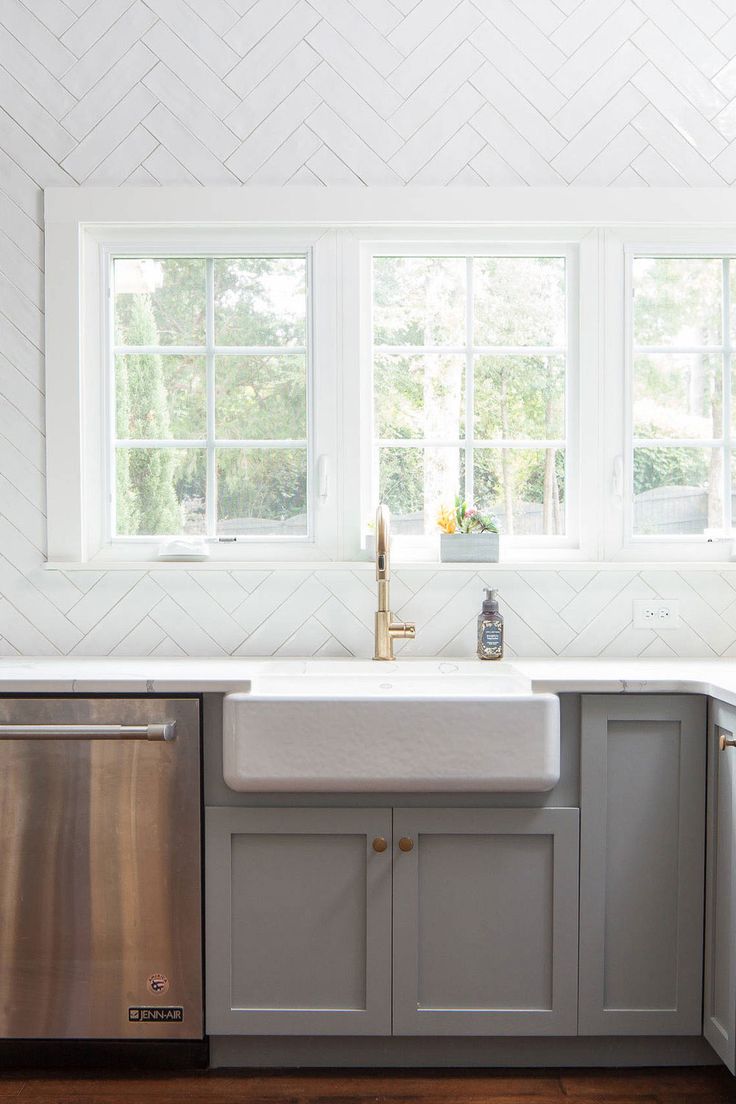 a kitchen with gray cabinets, white counter tops and stainless steel dishwasher in the center