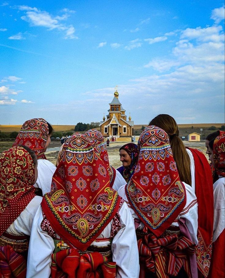 several people wearing red and white clothing standing in front of a building with a golden dome