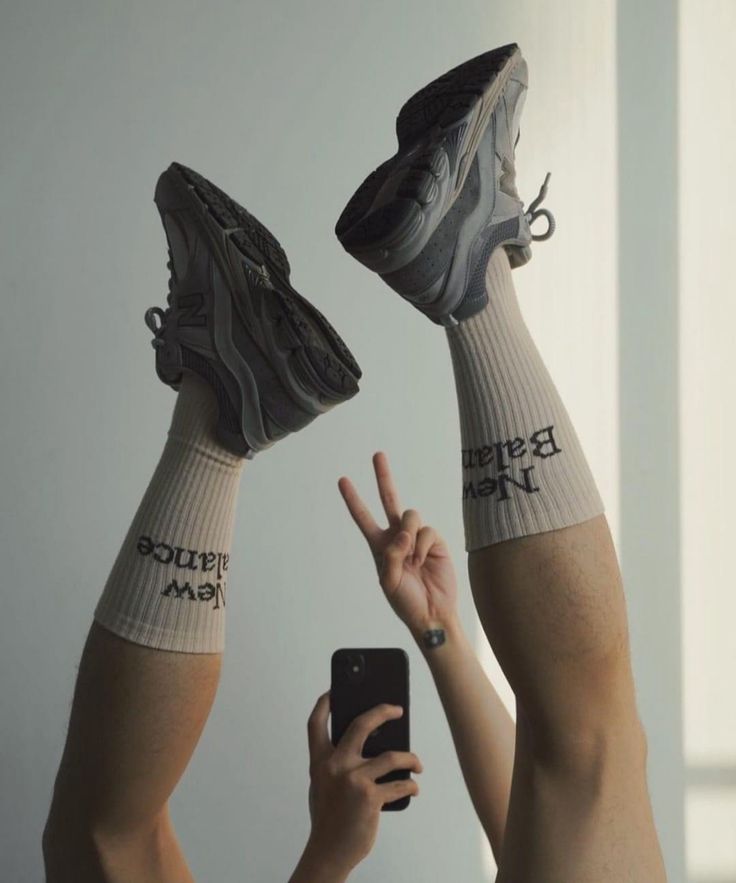 two people with socks on their feet are holding up cell phones and pointing at them