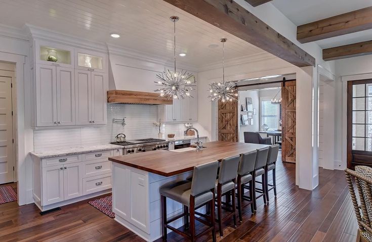 a large kitchen with white cabinets and wooden floors