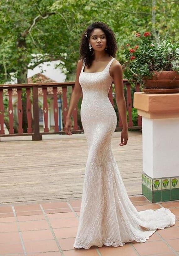 a woman in a white wedding dress standing on a brick floor next to a potted plant