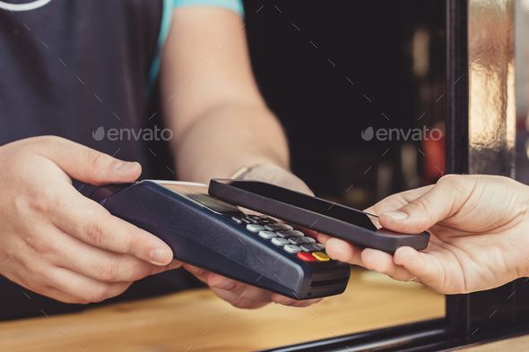 a man holding a remote control in his hand while another person is using the phone