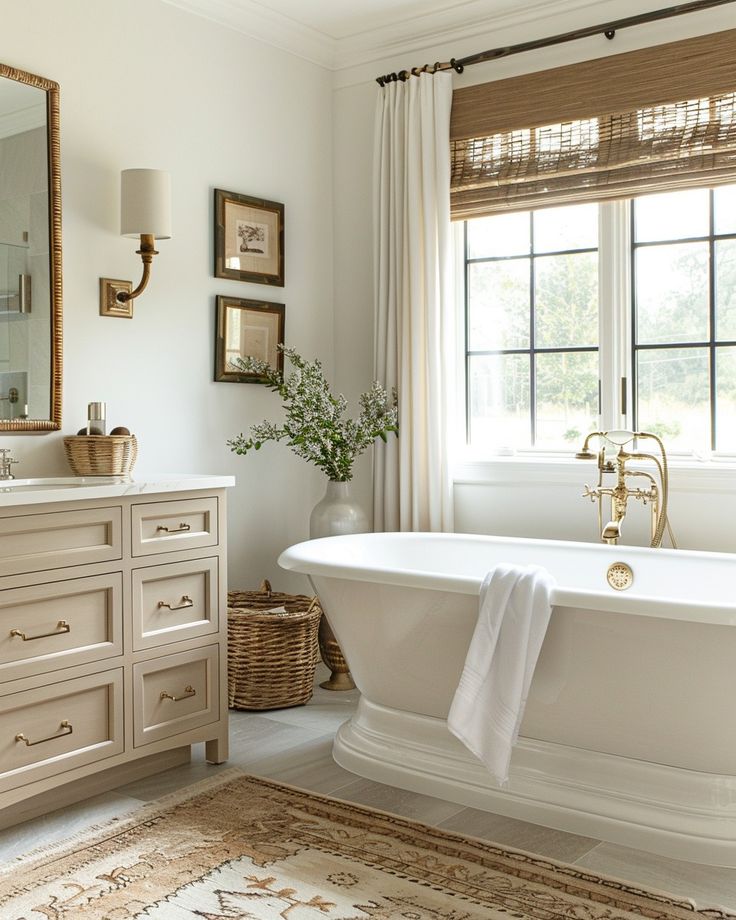 a white bath tub sitting under a window next to a sink in a bathroom with a rug on the floor