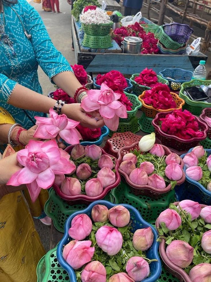 a woman is selling flowers at an outdoor market