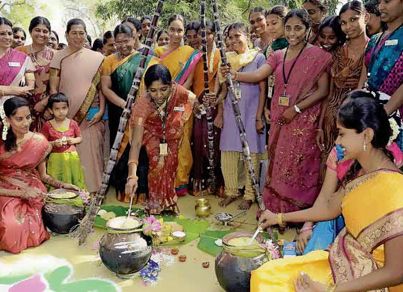 a group of women standing around each other in front of a pot and bowl on the ground