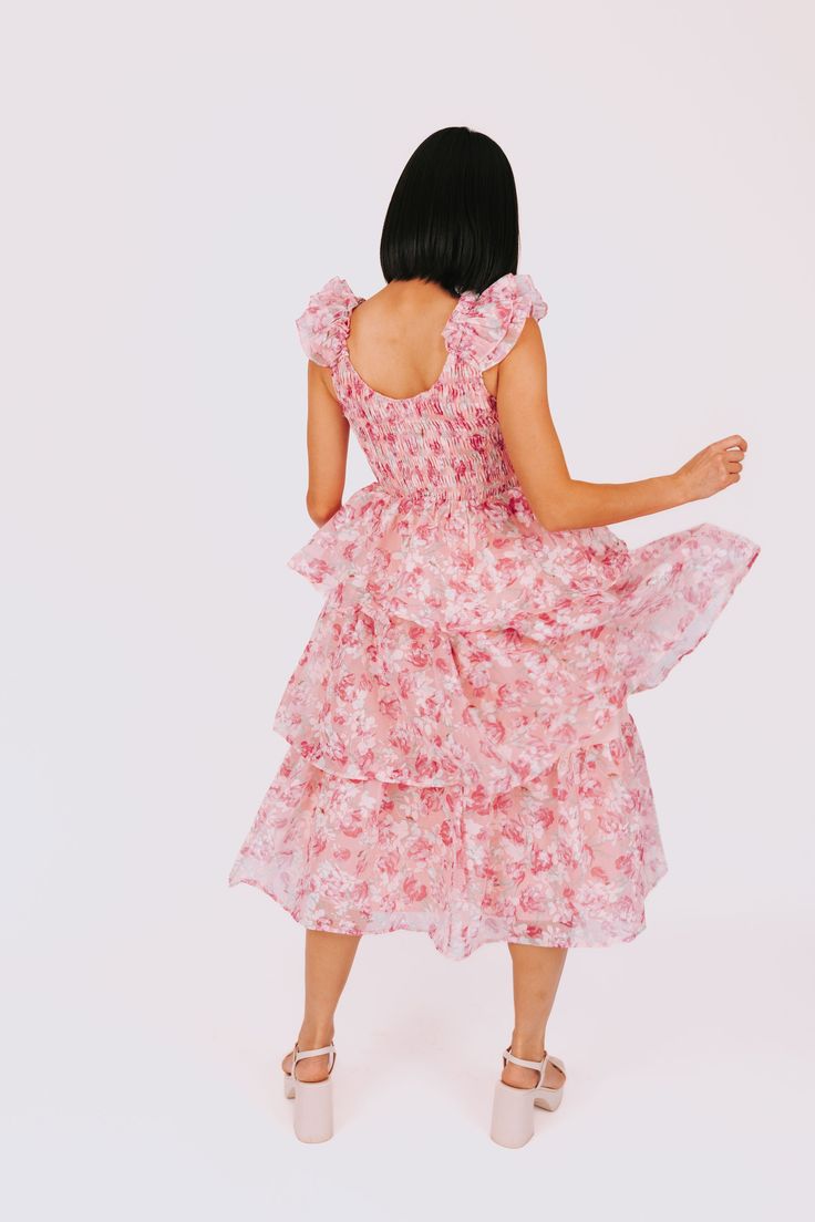 This fun and flirty dress will take you Through The Years with its ruffle straps and smocked bodice. The tiered design adds a playful touch, and the floral pattern adds a dash of whimsy. Perfect for any occasion, this dress will have you looking and feeling confident. Details Ruffle straps Smocked bodice Tiered Floral pattern Sizing Approximate measurements: SIZE LENGTH BUST Small 45" 30" Medium 46" 32" Large 47" 34" Fabric has stretch in the bodice Model is 5’7 wearing small Material 100% Polye Pink Smocked Dress With Ruffle Hem And Straps, Pink Tiered Smocked Dress With Ruched Details, Pink Tiered Ruffle Sleeveless Dress, Pink Tiered Ruffle Dress With Floral Print, Playful Pink Floral Dress With Ruffles, Flirty Dresses, Smocking, Bodice, Dresses For Sale