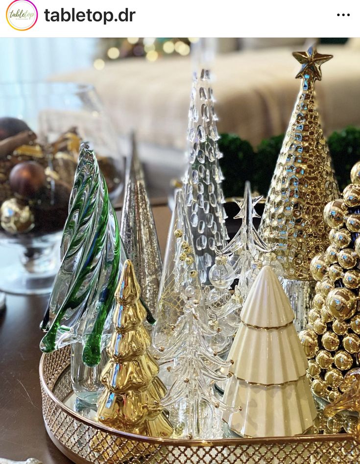 there are many small christmas trees in this tray on the table, and one is gold