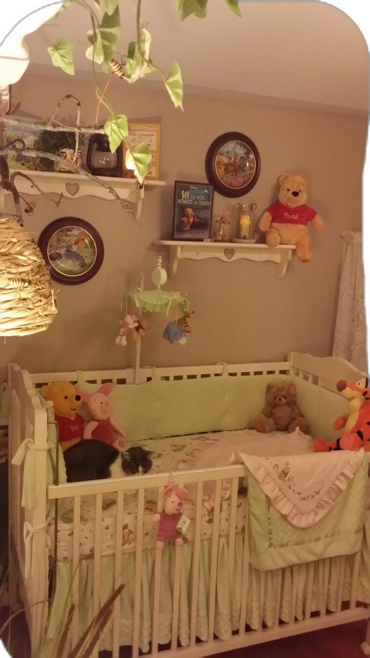 there is a crib with stuffed animals in it and pictures on the wall above