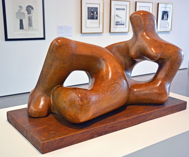 a wooden sculpture sitting on top of a white table next to framed pictures in a room