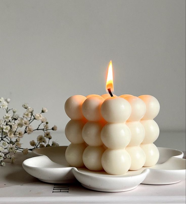 a white candle sitting on top of a plate