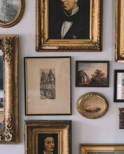 a wall with many framed pictures and paintings on it