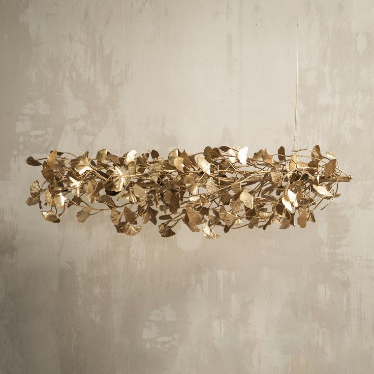 a gold leaf chandelier hanging from the ceiling in front of a white wall