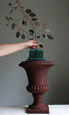 a hand is placing a green box on top of a vase