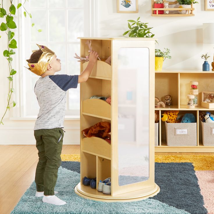 a little boy standing in front of a tall book shelf filled with books and toys