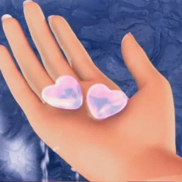 two heart shaped pink and white rings sitting on top of a person's hand