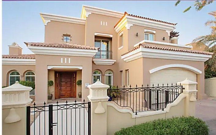 a house that has a gate in front of it and some bushes around the fence