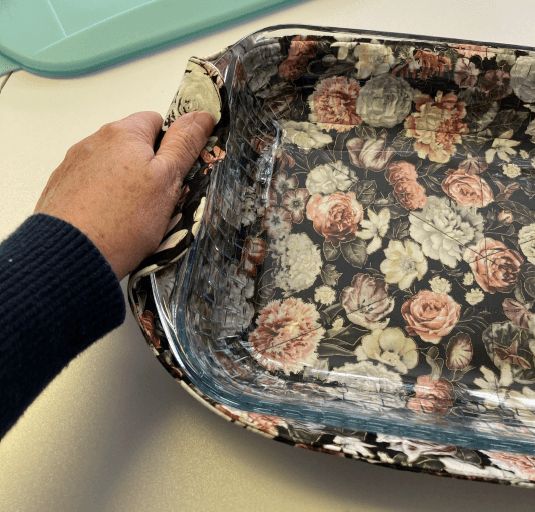 a person with their hand on a flowered tray that is sitting on a table