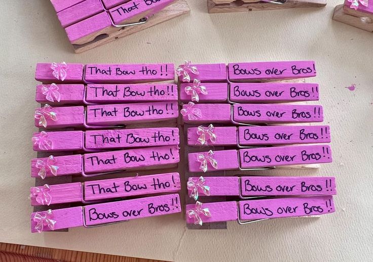 several pieces of pink wood with words written on them and bows attached to them, sitting on a table