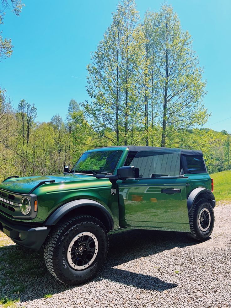 a green truck parked on top of a gravel road