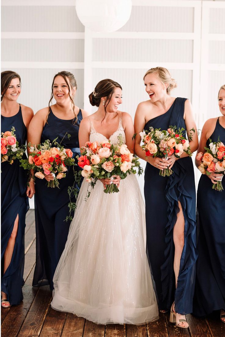 the bride and her bridesmaids are all wearing navy blue dresses with orange bouquets