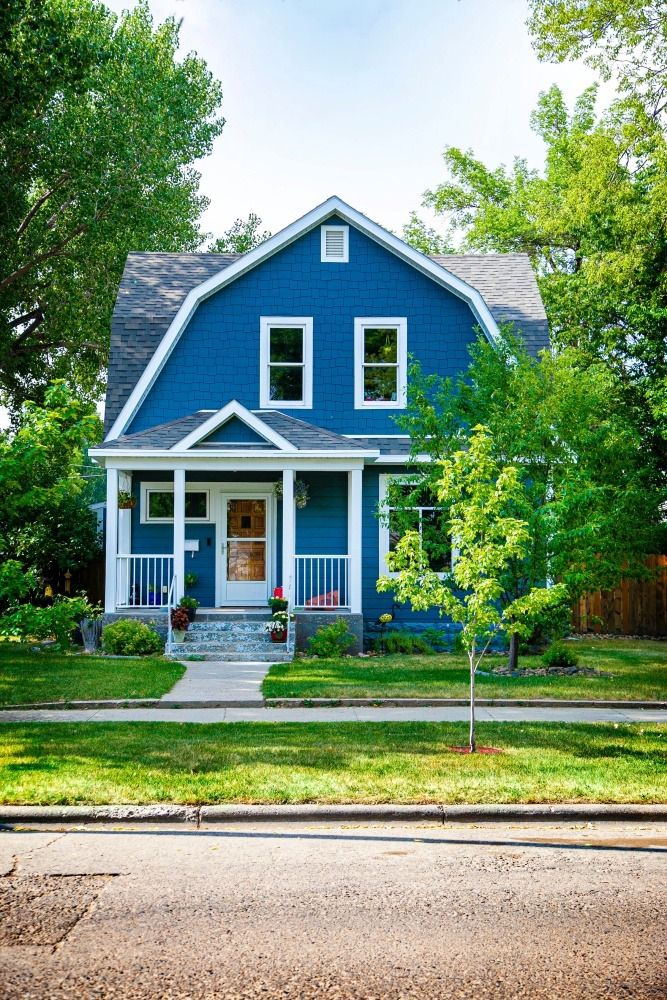 a blue house with white trim on the front porch and two story windows is shown