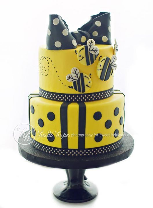 a three tiered cake with polka dots and bows on the top is decorated in yellow and black