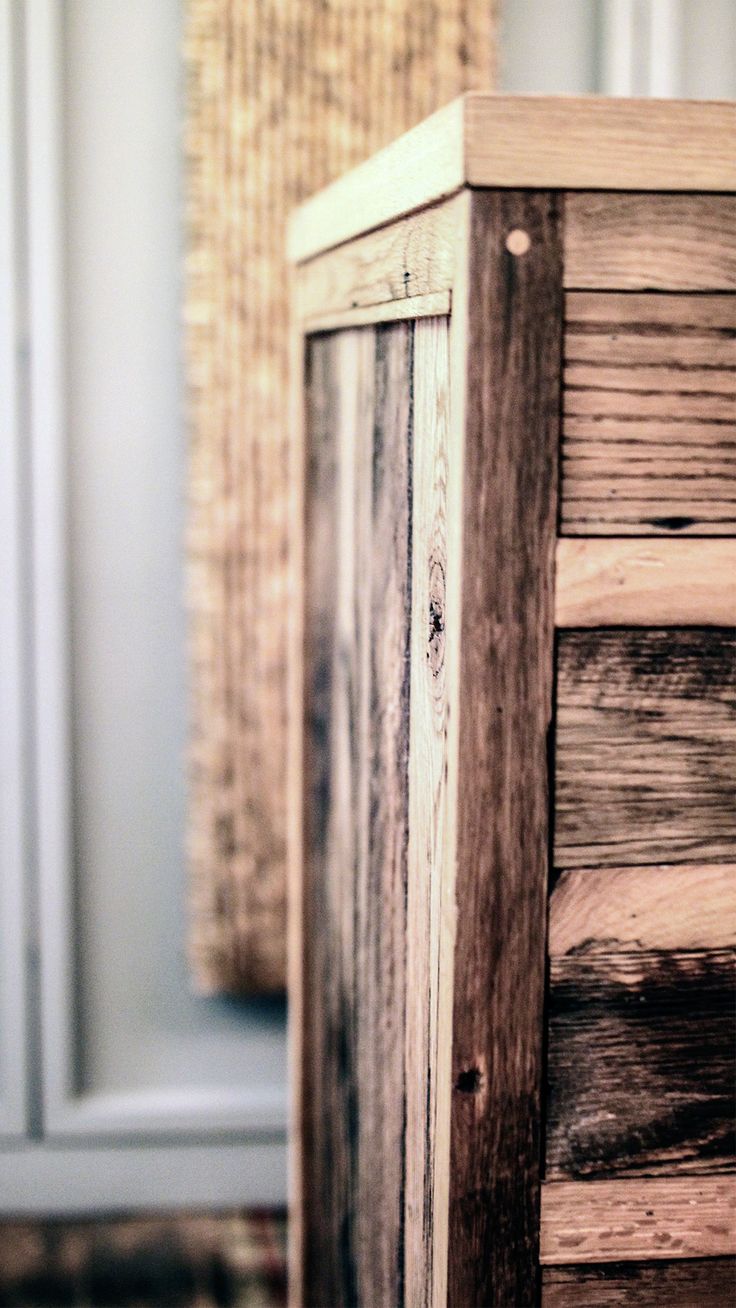 an old wooden cabinet sitting in front of a white wall with a window behind it