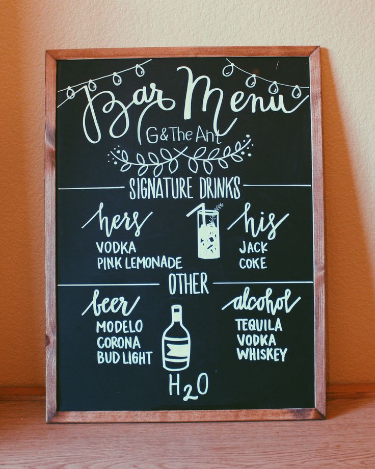 a blackboard sign that has some writing on it with drinks and wine in front of it