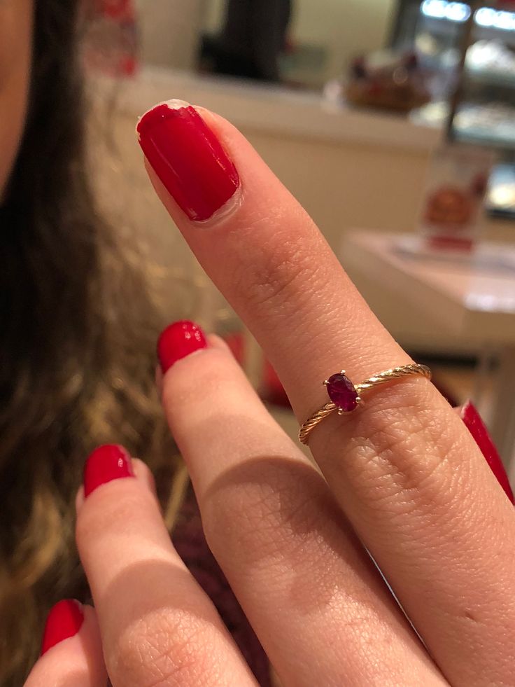 a woman's hand with a red manicure and a gold ring on it