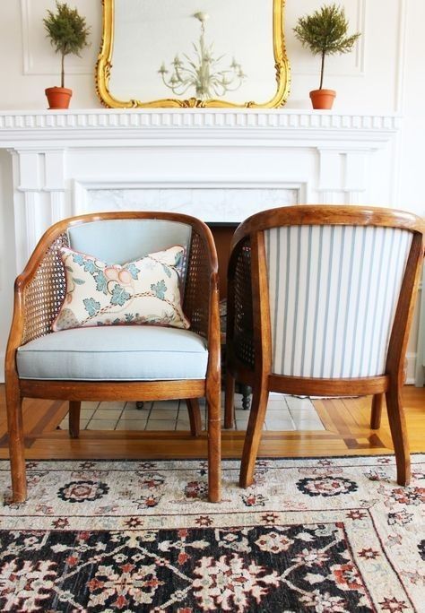 two chairs sitting next to each other on top of a rug in front of a fireplace