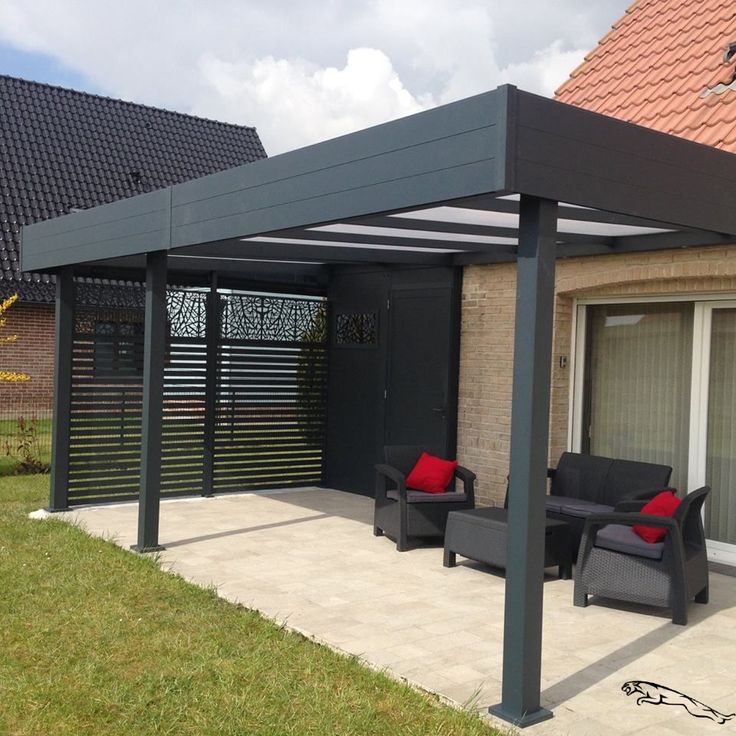 a patio covered in black furniture next to a brick building with red pillows on it