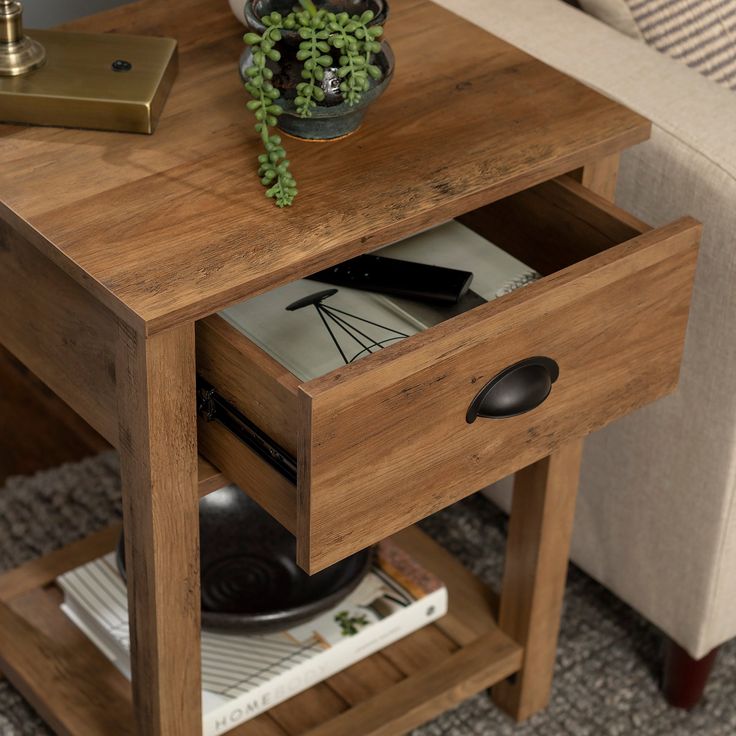 a small wooden table with a plant on top and magazines in the bottom drawer next to it