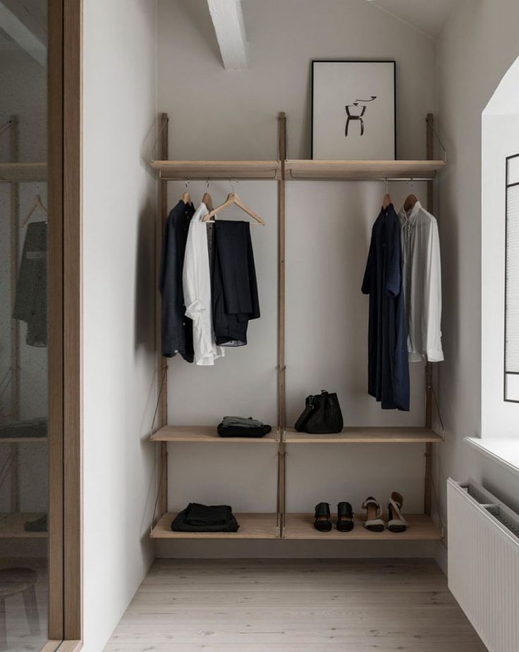 an open closet with clothes and shoes hanging on the wall next to a radiator