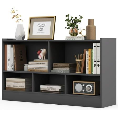 a book shelf with books and other items on it, including an empty framed photograph