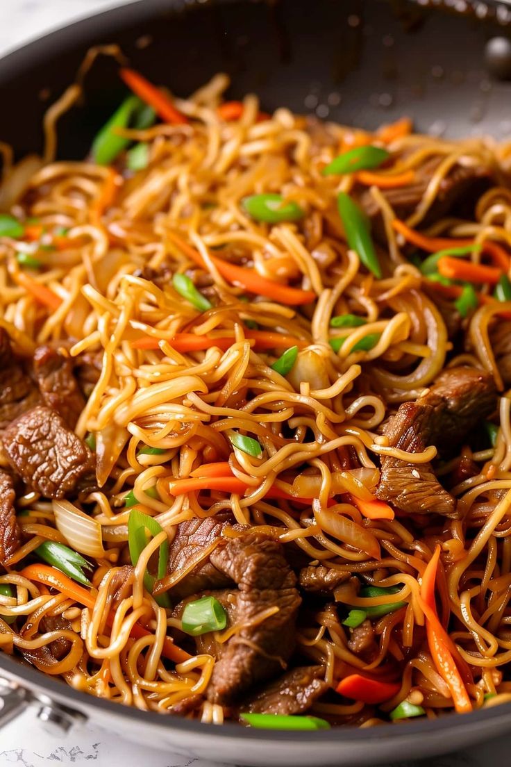 beef lo mein with carrots and green peppers in a skillet