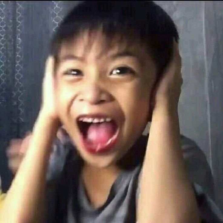 a young boy holding his head in front of his face and making a funny face