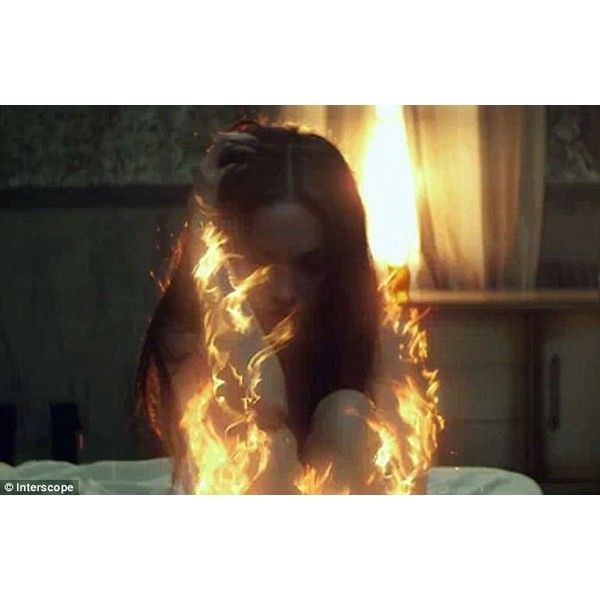 a woman sitting on top of a bed in front of a window covered in fire