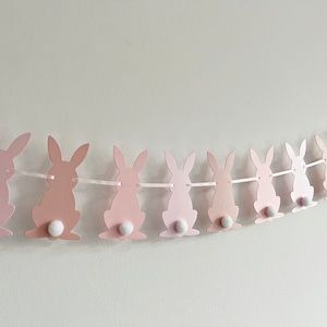 pink and white bunting with bunny ears hanging on the wall next to it's string