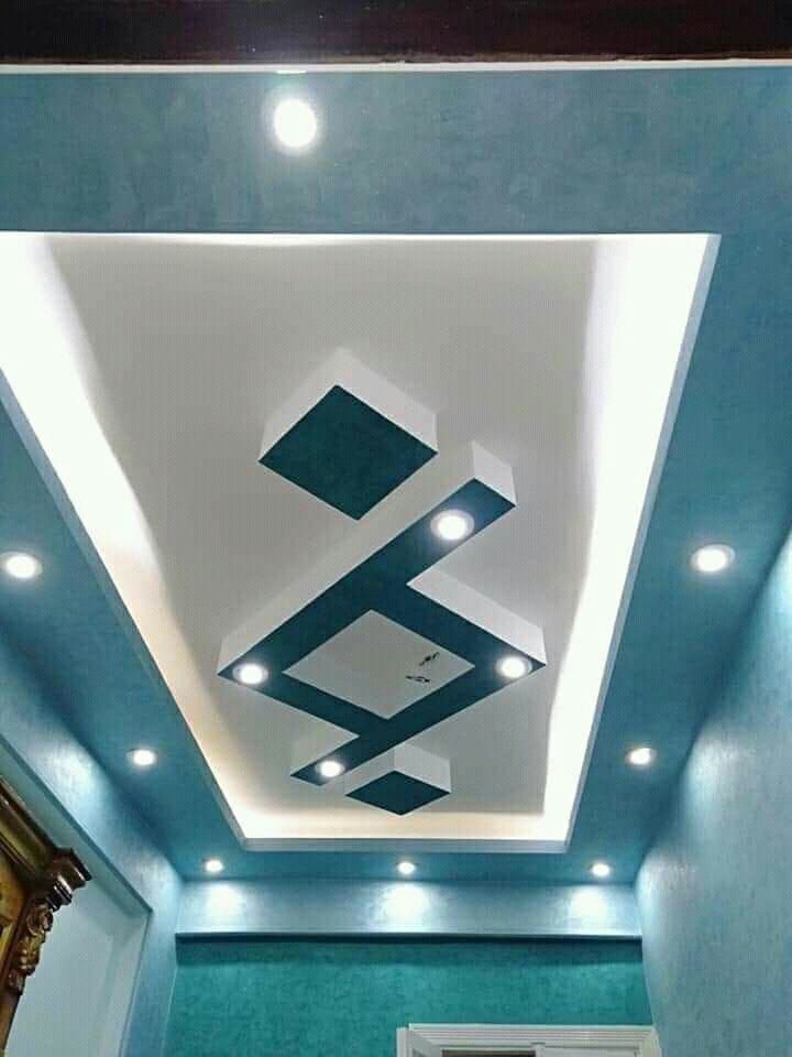 a room with blue walls and white ceiling tiles on the ceiling is lit by recessed lights