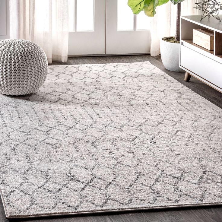 a white rug with an intricate design on the floor in front of a large window